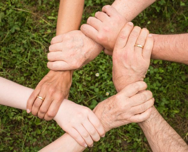 remote team hands Manage Remote Distributed Teams